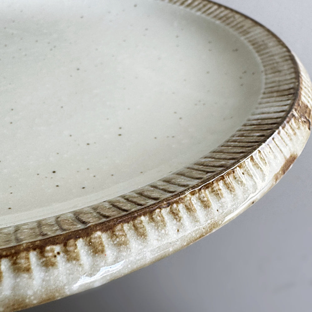 Raised rim dinner plate in cream white glaze. Fuchisabi Kohiki Plate made in Gifu prefecture, Japan. Mino Ware. Available at Toka Ceramics.