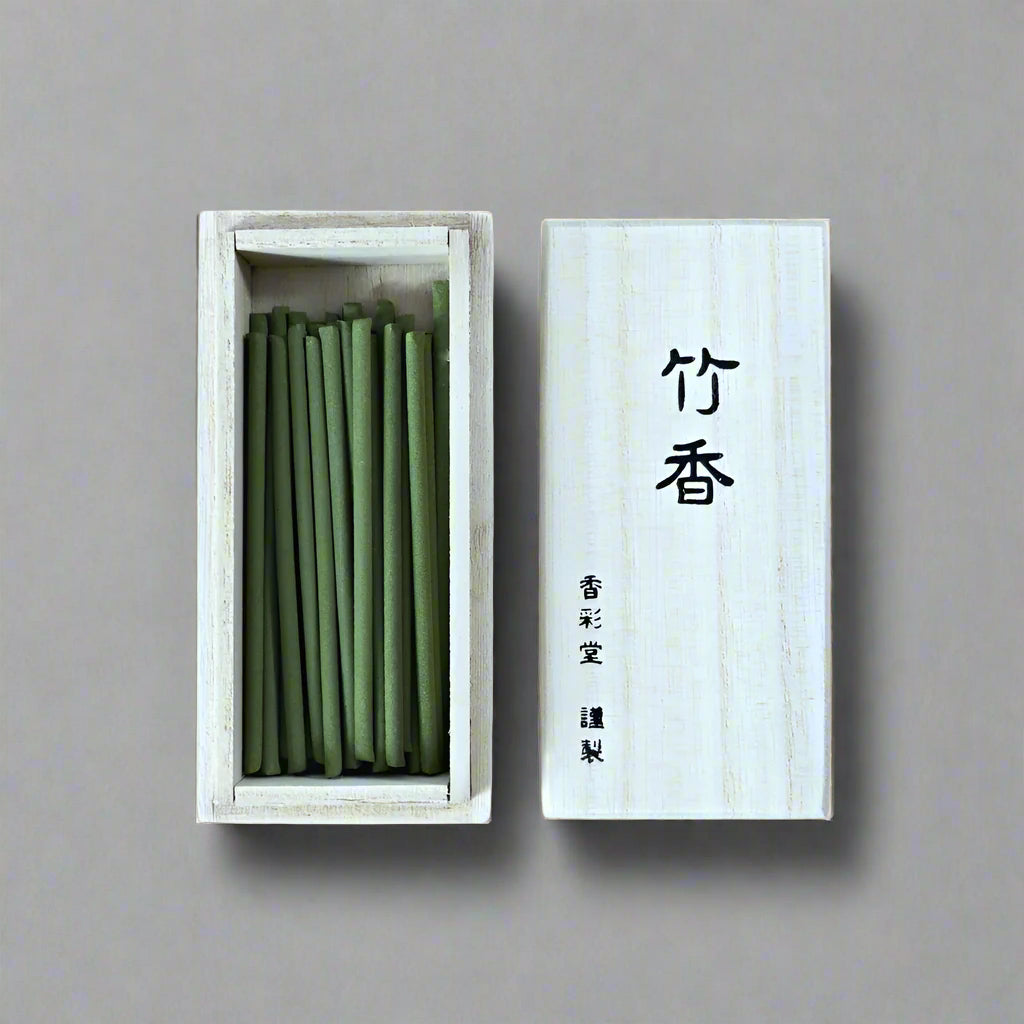Top-down view of open paulownia box showing green Takekou incense sticks next to the calligraphy lid, from Senju Living.