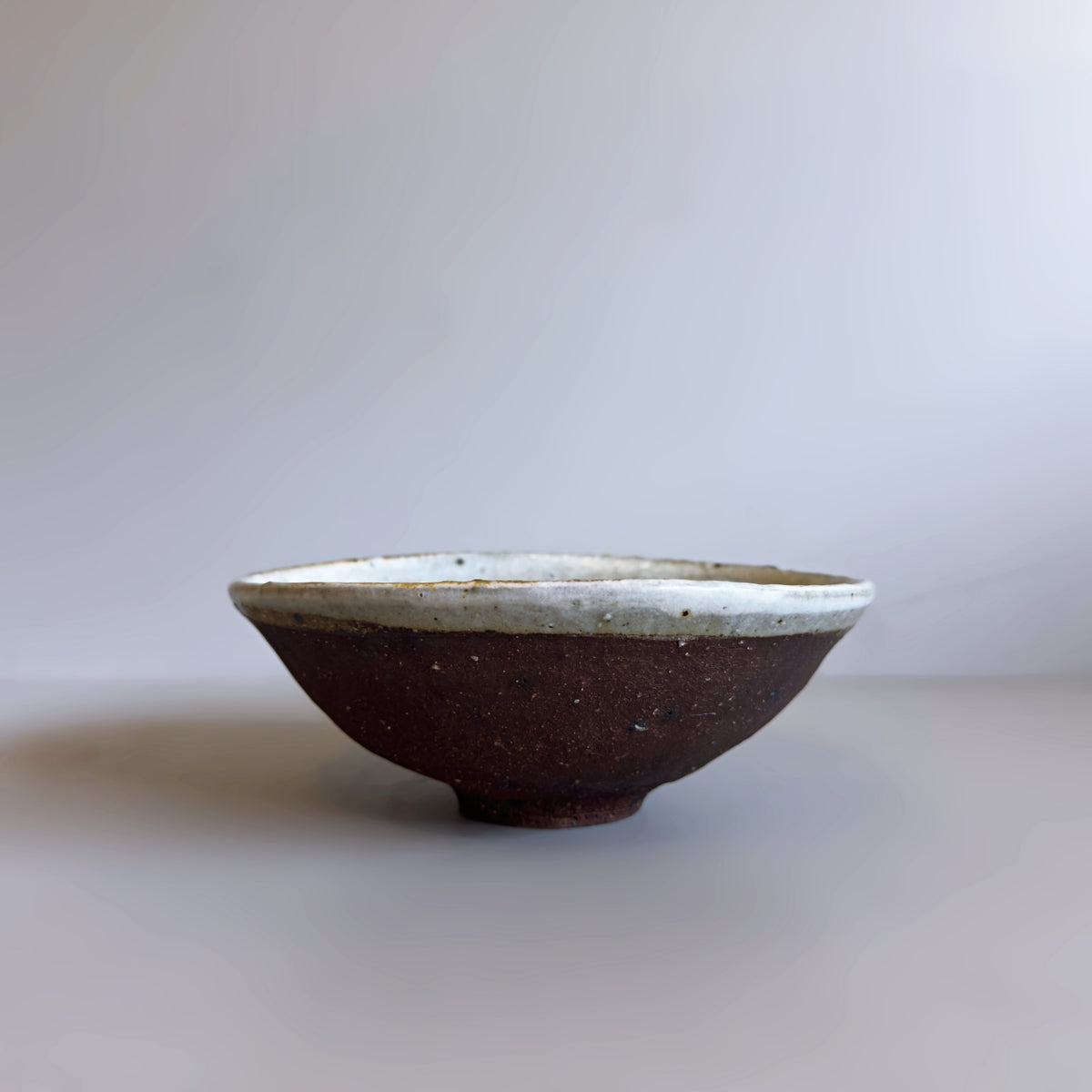 Side profile of a handmade vintage Japanese ceramic bowl with a clean white glazed rim, from Senju Living.