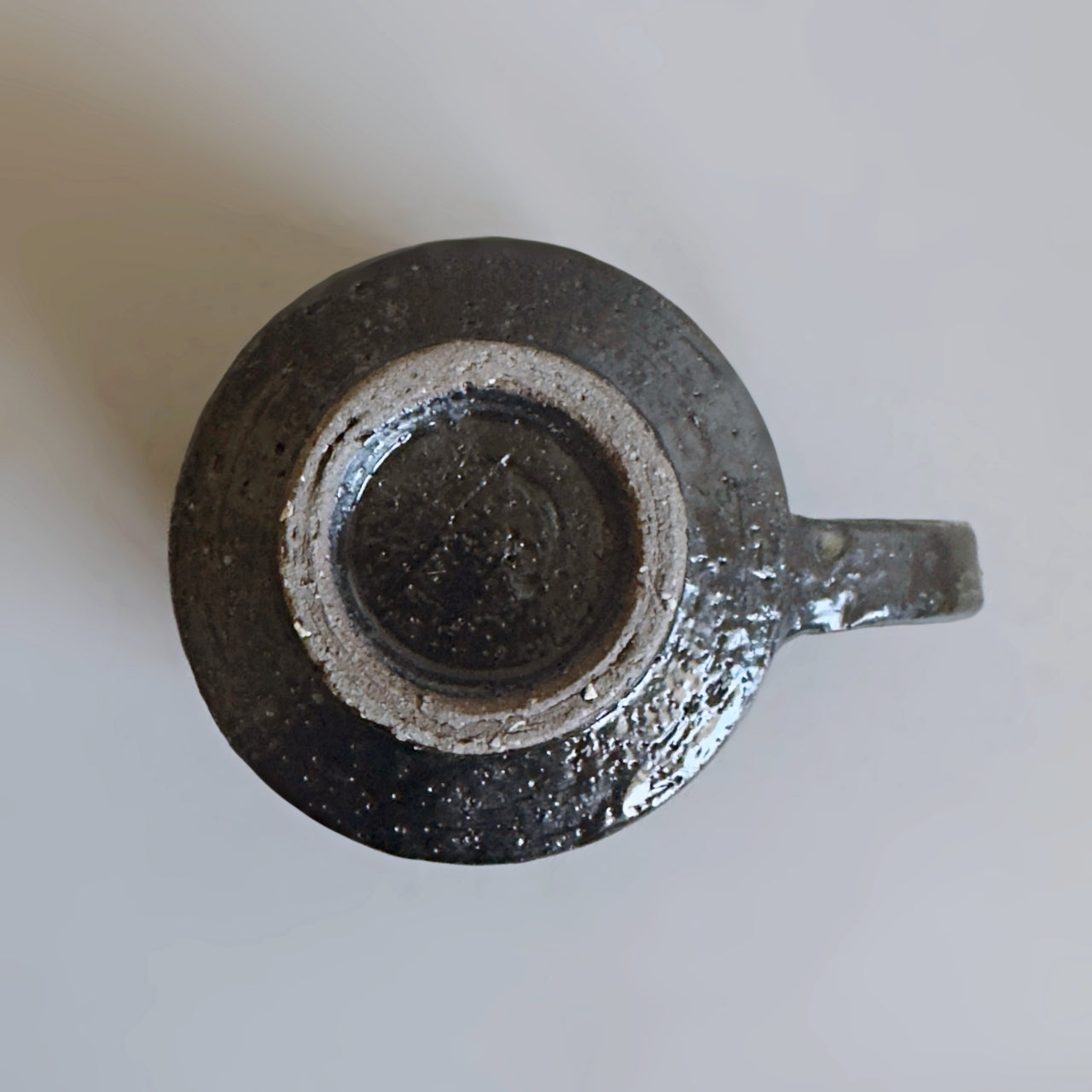 Top-down view of the unglazed ring on the bottom of a black Minoware stoneware mug, from Senju Living.