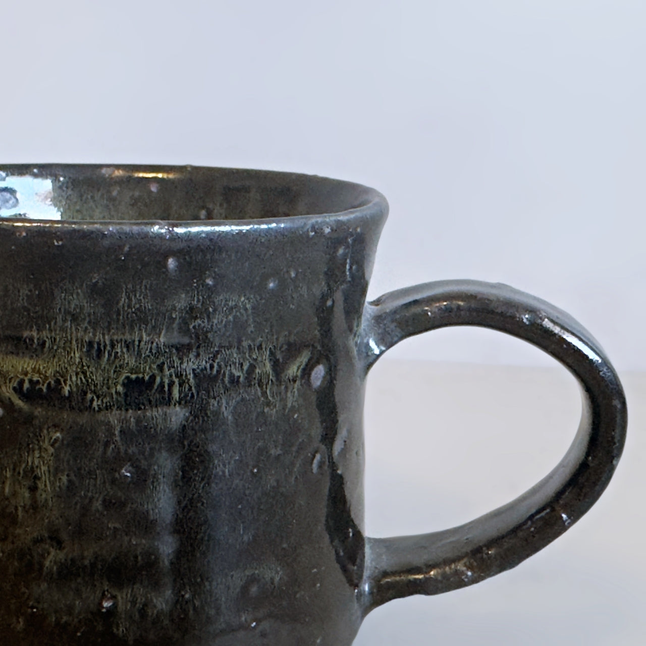 Close-up of the sturdy, comfortable handle on a rustic black Minoware stoneware mug, at Senju Living.