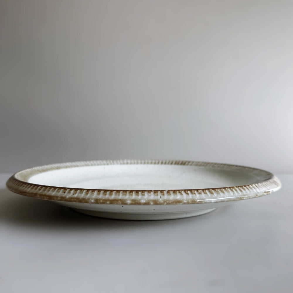 Raised rim dinner plate in cream white glaze. Fuchisabi Kohiki Plate made in Gifu prefecture, Japan. Mino Ware. Available at Toka Ceramics.