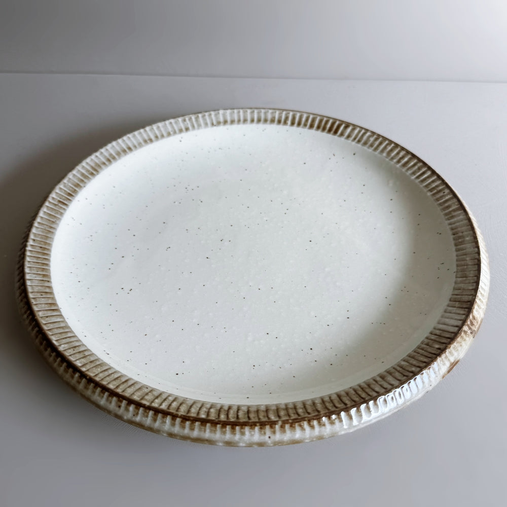 Raised rim dinner plate in cream white glaze. Fuchisabi Kohiki Plate made in Gifu prefecture, Japan. Mino Ware. Available at Toka Ceramics.