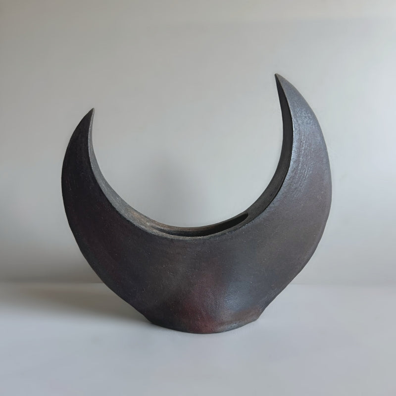 A handcrafted Crescent Vase made by Tsugaru Kanayama Pottery in Japan, featuring a unique crescent moon shape and dark earthy tones.