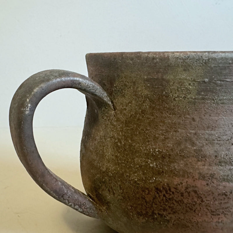 A rustic, handcrafted ceramic mug with a round shape and an earthy, textured surface, featuring shades of brown and gray, made by Tsugaru Kanayama pottery in Japan.