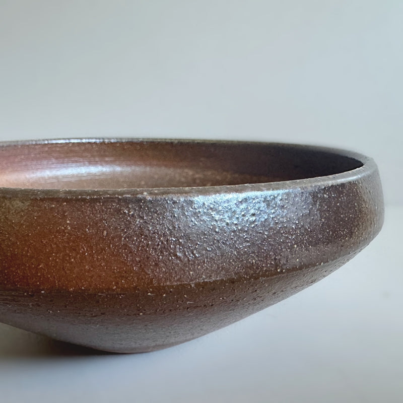 An earthy brown medium sized bowl without glaze. Handcrafted by Tsugaru Kanayama Pottery in Japan. Available at Toka Ceramics.