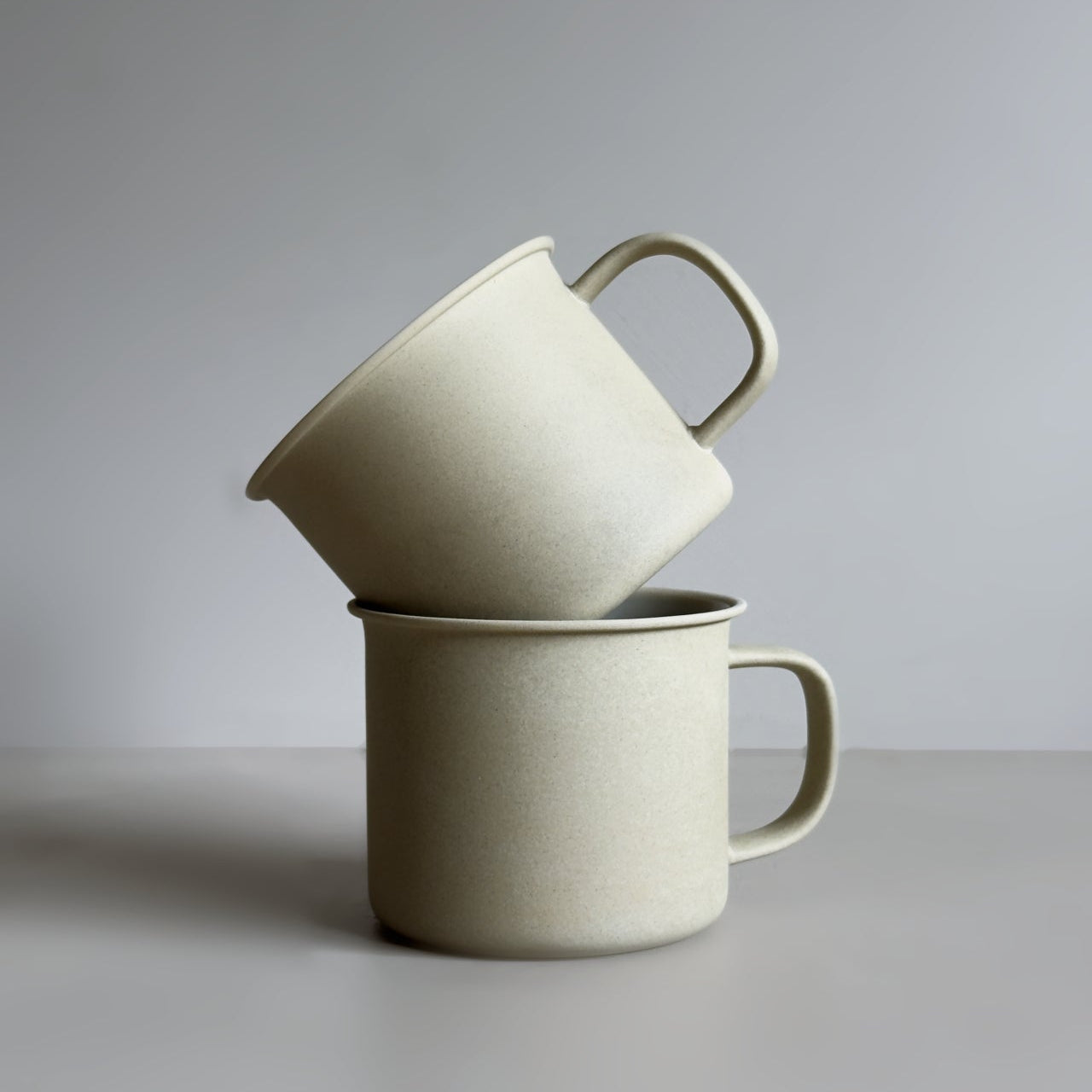 Two stacked ceramic mugs on a plain background