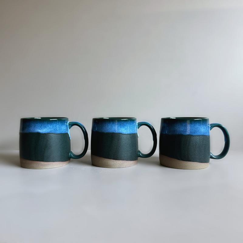 Three dark blue TOKA ceramic mugs lined up to show unique glaze variations, handmade Mino ware from Tajimi, Japan.