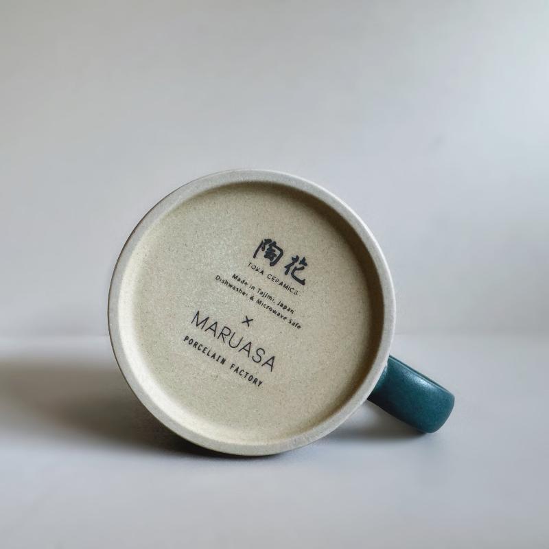 Bottom base of a TOKA ceramic mug in dark blue glaze showing the Maruasa Porcelain Factory stamp, handmade Mino ware from Tajimi, Japan.