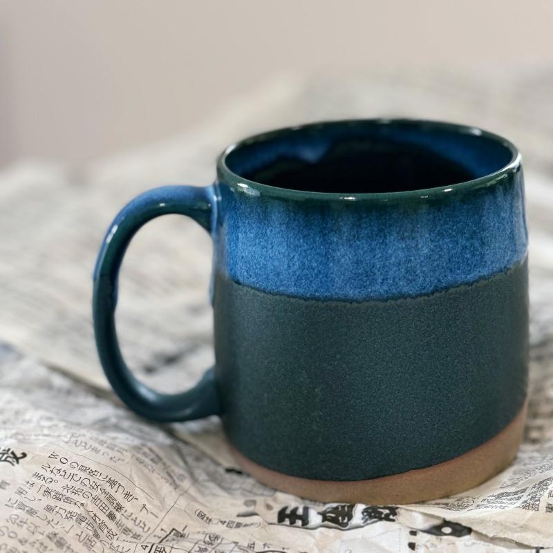 Dark blue TOKA Japanese ceramic mug on a Japanese newspaoer, minimalist Wabi-sabi aesthetic.”