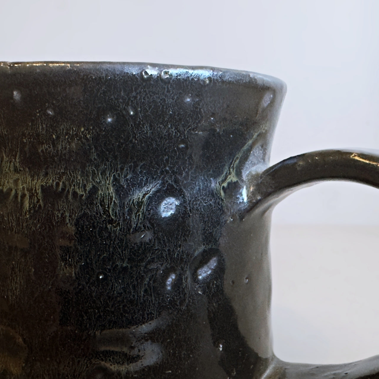 Close-up of the glossy, textured black glaze with golden-brown speckles on a Minoware ceramic mug, at Senju Living.