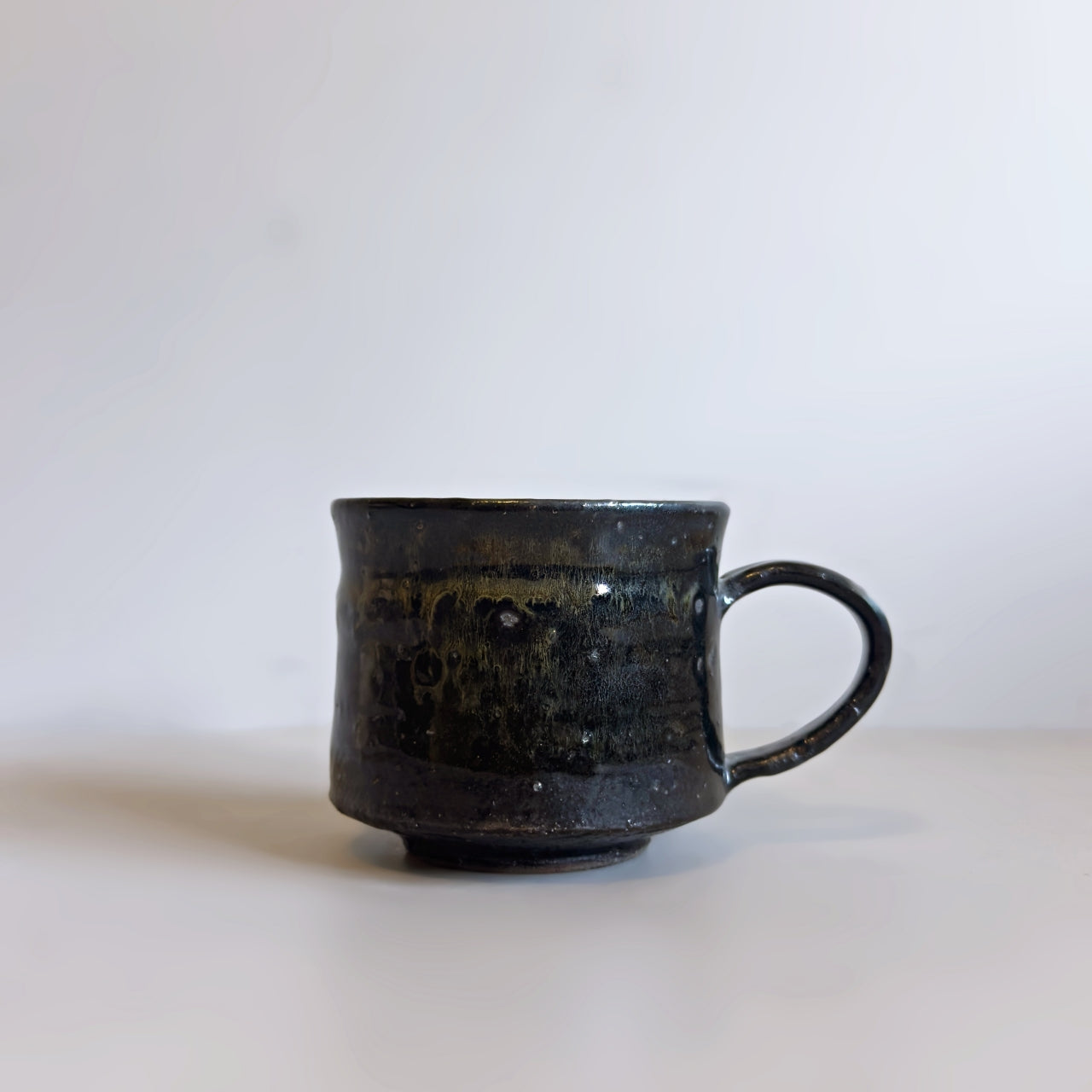 Side profile of a modern, rustic black Minoware ceramic coffee mug with a sturdy handle, from Senju Living.
