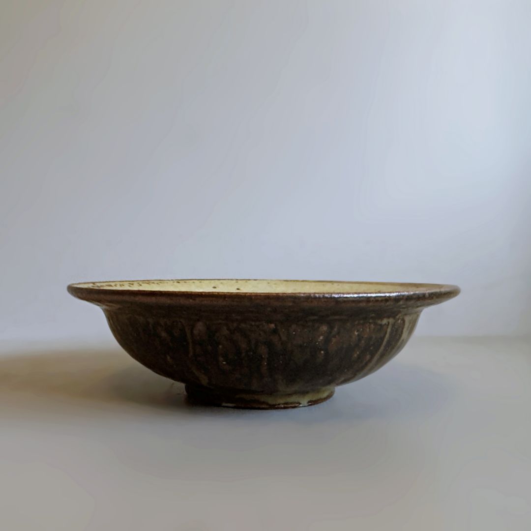 Side view of the shallow brown bowl with a wide rim and raised foot from Senju Living